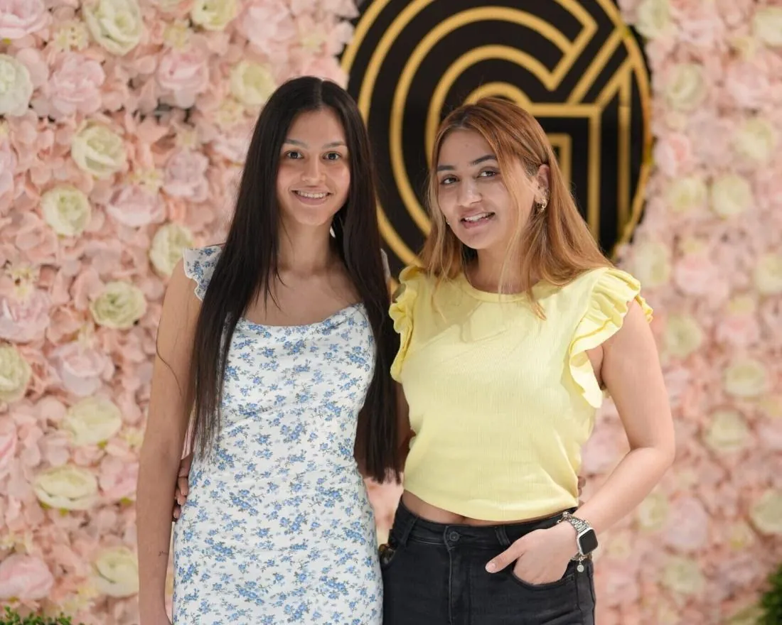 Two clients in front of the Glam & Go flower wall and gold monogram