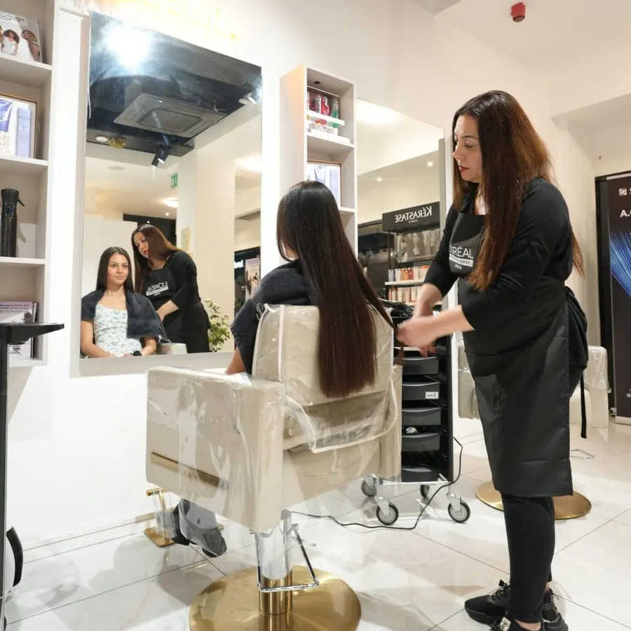 A stylist sectioning long hair at a styling station